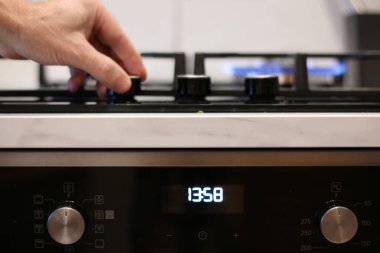 Bir adamın eli mutfak sobasının gazını yakıyor. Bir aşçı yemek pişirmek için gaz sobasını yakar..