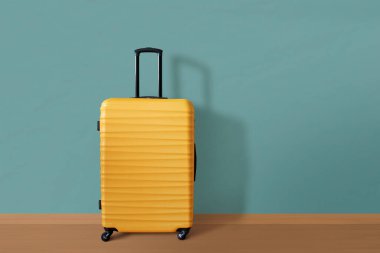 Duvara dayalı yeni sarı bavul. Seyahat ve tatil kavramı.