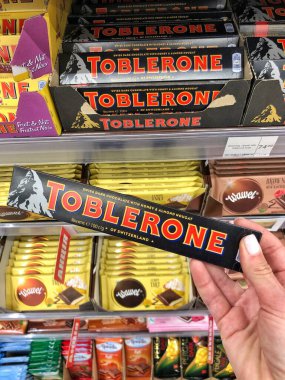25.03.2023 Ukrayna, Harkov Çikolatalı Toblerone ellerinde. Raflarda nefis çikolatalar var. Ballı bademli İsviçre çikolatası. 