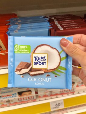 03.10.2023, Harkov, Ukrayna. Hindistan cevizi kremalı Ritter Sport marka çikolataya yakın çekim. Bir kadının elinde çikolata.