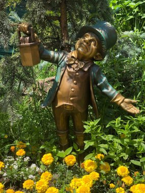 Çiçek bahçesinde bronz bir leprikon heykeli.