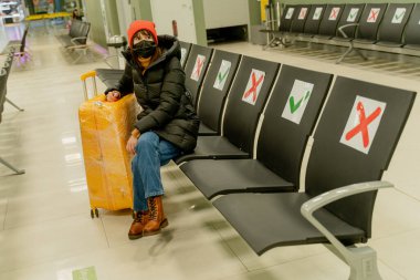 Yellow suitcase. A woman with a yellow suitcase and a medical mask.