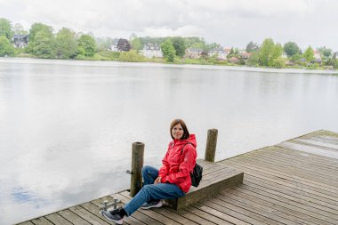 Yağmur. Üzerine yağmur damlayan bir kadın parkta oturuyor..