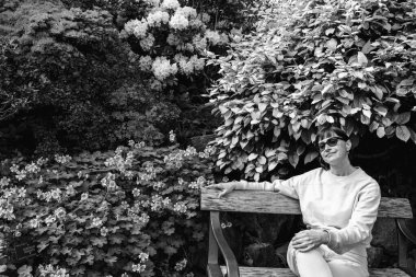 Çiçek açan ağaçlar. Kız çiçek açan ağaçların yanındaki bankta oturuyor..