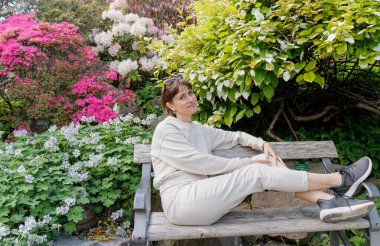 Çiçek açan ağaçlar. Kız çiçek açan ağaçların yanındaki bankta oturuyor..