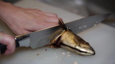 Uskumru. Uskumru balığı mutfak tahtasıyla kesilir..