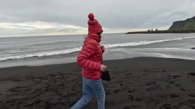 Kız siyah plaj boyunca koşuyor. İzlanda.