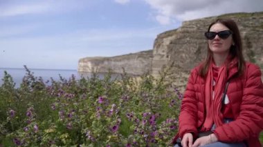 Bir kız güzel bir manzaranın arka planında oturur. Malta.