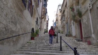 Eski kasabada bir kız merdivenlerden aşağı iniyor. Malta.