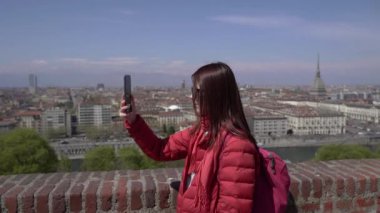 Torino. Bir kız telefonuyla şehri filme çekiyor. İzleme platformunda bir kız.