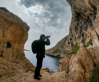 Malta. Bir adam Gozo adasındaki bir kayanın üzerinde fotoğraflandı..