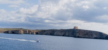 Malta 'nın kayalık kıyılarından bir tekne geçiyor. Kayanın görüntüsü.