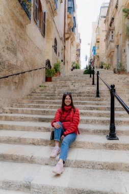 Eski kasabadaki merdivenlerde bir kız oturuyor. Malta.