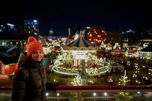 Kerst Pretpark Vrouw Glimlacht Kijkt Naar Gloeiende Bezienswaardigheden — Stockfoto
