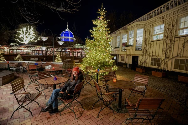 クリスマスアミューズメントパーク 女性が夜空のストリートカフェに座る ストック写真
