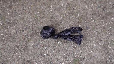 Yerde siyah küçük bir paket var. Çantadaki köpek dışkısı..