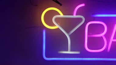 Barın girişinde neon bir tabela var. Tabelada bir bardak resmi var..