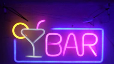 Barın girişinde neon bir tabela var. Tabelada bir bardak resmi var..