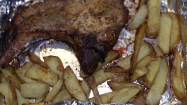 Pişmiş et parçası. Folyoda patates ve kızarmış biftek..