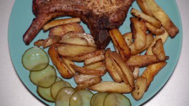 Pişmiş et parçası. Mavi tabakta kızarmış biftek ve patates..