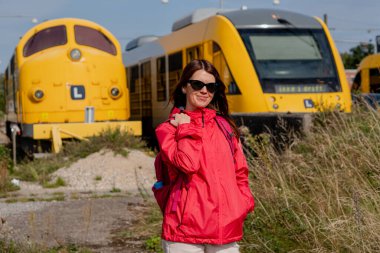 Bir kadın arkadan trene doğru yürüyor. Tren istasyonu..