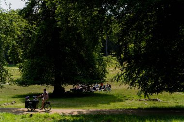 Kopenhag 'da. Danimarka. 06 Haziran 2023. İnsanlar parkta dinleniyor. İnsanlar bisiklet sürüyor..