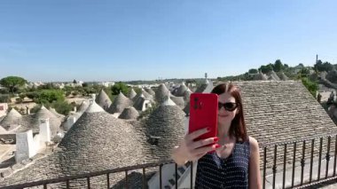 Bir kadın Apulia 'da beyaz trulli' nin önünde selfie çekiyor..