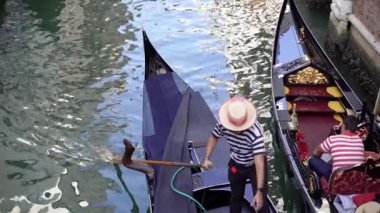 Kürekli bir gondolcu kanaldaki gondolu kontrol eder..