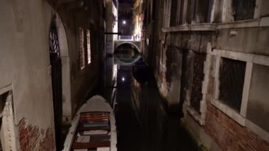 Geceleri Venedik. İnsanlar dar bir kanalın köprüsü boyunca yürür.