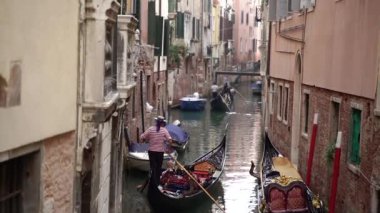 Kürekli bir gondolcu kanaldaki gondolu kontrol eder..