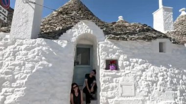 İki kız evin girişinin yanında oturuyor. Apulia 'daki beyaz evler.