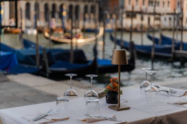 Arkasında Venedik kanalı olan bir restoran. Bir sokak restoranında masa ayarı..