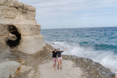 Fırtınanın arka planında ellerini sallayan iki kız..