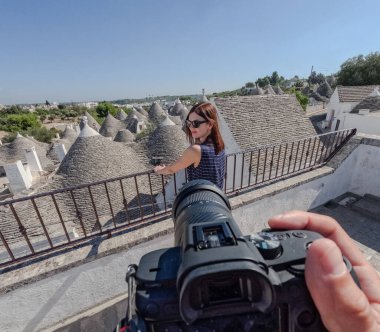 Apulia 'da beyaz trulli önünde poz veren bir kadın.