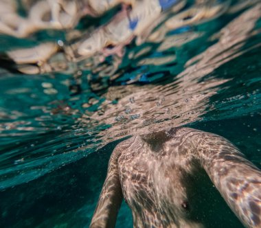 Erkek gövdesi suyun altında. Adam turkuaz suda yüzüyor..