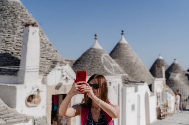 Bir kadın Apulia 'da beyaz trulli' nin önünde selfie çekiyor..