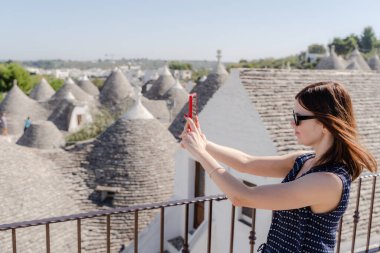 Bir kadın Apulia 'da beyaz trulli' nin önünde selfie çekiyor..