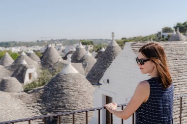 Apulia 'da beyaz trulli önünde poz veren bir kadın.