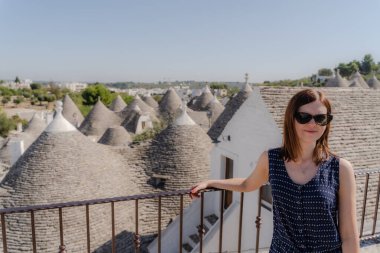 Apulia 'da beyaz trulli önünde poz veren bir kadın.