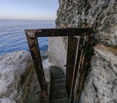 Sahile giden yol. Resimli kayalık bir plaja merdivenler.