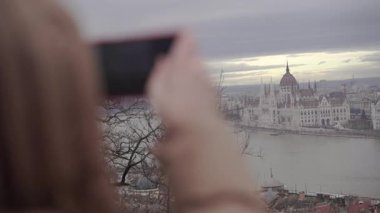 Bir kadın telefonuyla bir binanın fotoğrafını çekiyor..