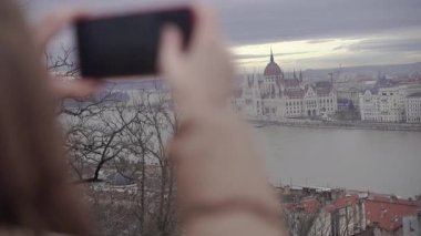 Bir kadın telefonuyla bir binanın fotoğrafını çekiyor..