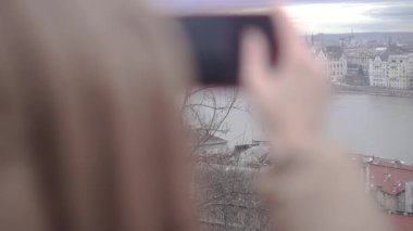 Bir kadın telefonuyla bir binanın fotoğrafını çekiyor..