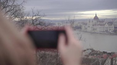 Bir kadın telefonuyla bir binanın fotoğrafını çekiyor..