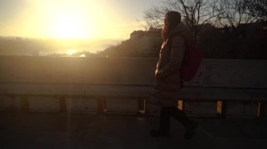 Şafak Bir kadın izleme platformunda bir caddede duruyor ve şehre bakıyor..