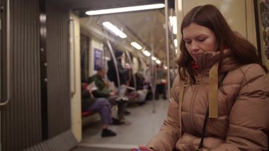 Metro polisi. Tren vagonunda giden bir kadın telefonuna bakıyor..