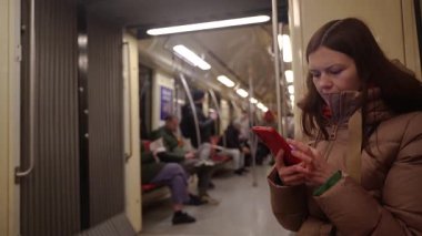 Metro polisi. Tren vagonunda giden bir kadın telefonuna bakıyor..