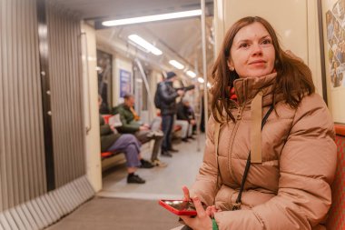 Metro polisi. Tren vagonunda giden bir kadın telefonuna bakıyor..