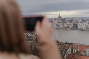 Bir kadın telefonuyla bir binanın fotoğrafını çekiyor..