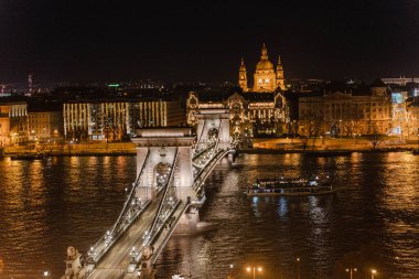 Gece şehri. Nehir boyunca aydınlık bir binaya bak.